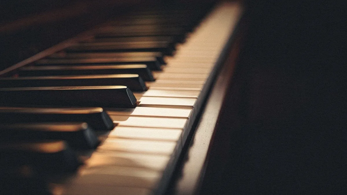 Close-up of warm-lit piano keys with one black key pressed, illustrating the single chromatic note a secondary dominant adds from outside the key