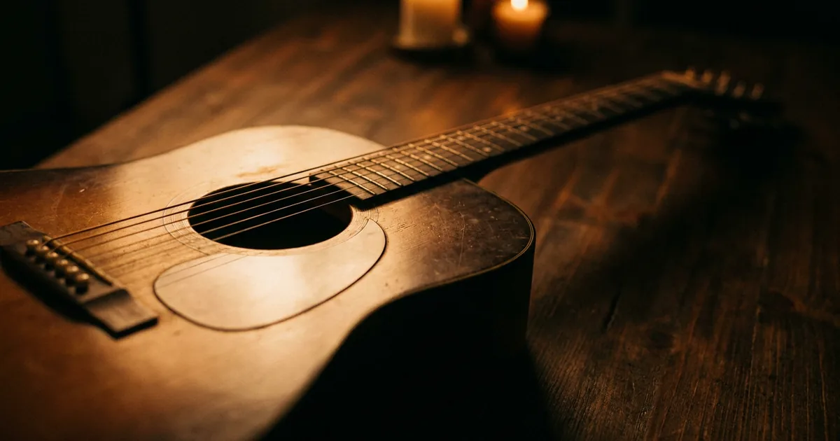 An acoustic guitar lying in low amber light, the instrument most songwriters reach for when writing a sad chord progression
