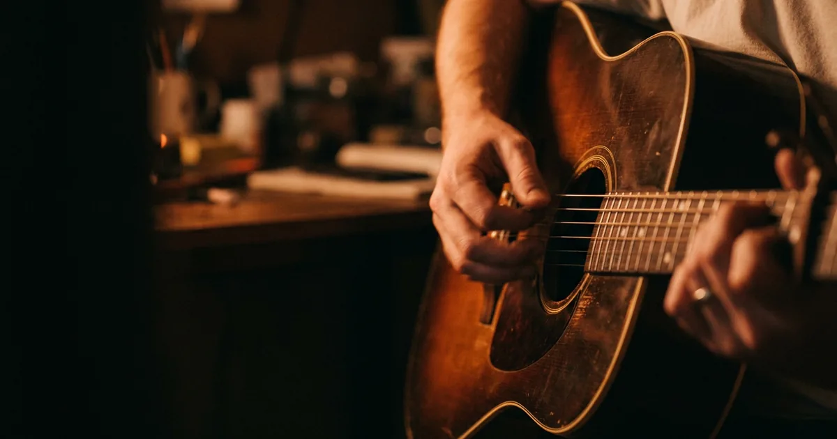 A songwriter strumming an acoustic guitar, one hand keeping the strum going while the other forms a chord on the neck, showing that a progression's feel comes from timing as much as from the chords
