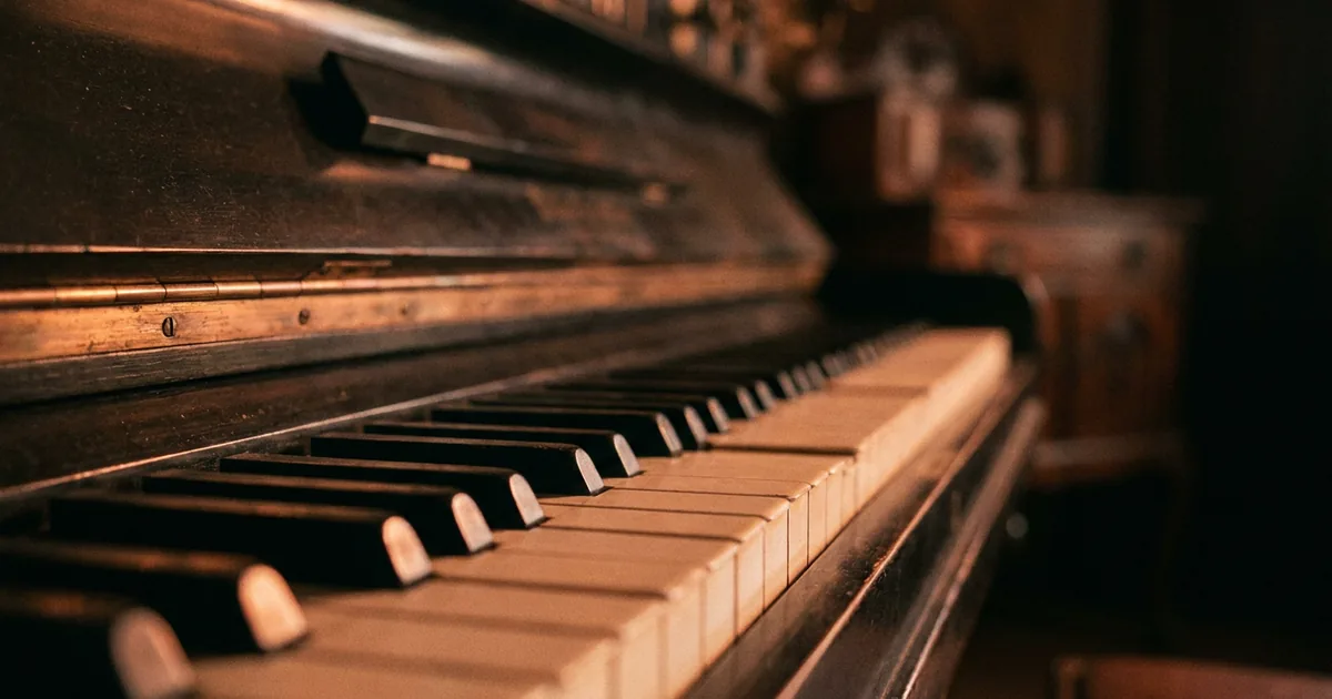 The history of syncopation in music: the keys of a worn upright piano lit from the side, the kind of instrument ragtime was written on.